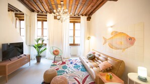 Un salón acogedor con un sofá, un televisor, una araña y un mural de peces en la pared.