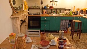 A kitchen with a dining table set for two, a large mirror, and a green accent wall. - Ostellin Genova Hostel (Genoa)