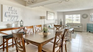 A dining area with a wooden table and chairs, a potted plant, and a wall with a motivational quote. - CRC 1108 - Ground Floor Condo Easy Pool Access (St Augustine)