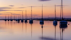 Een jachthaven met verschillende zeilboten afgemeerd in rustig water tijdens zonsondergang.