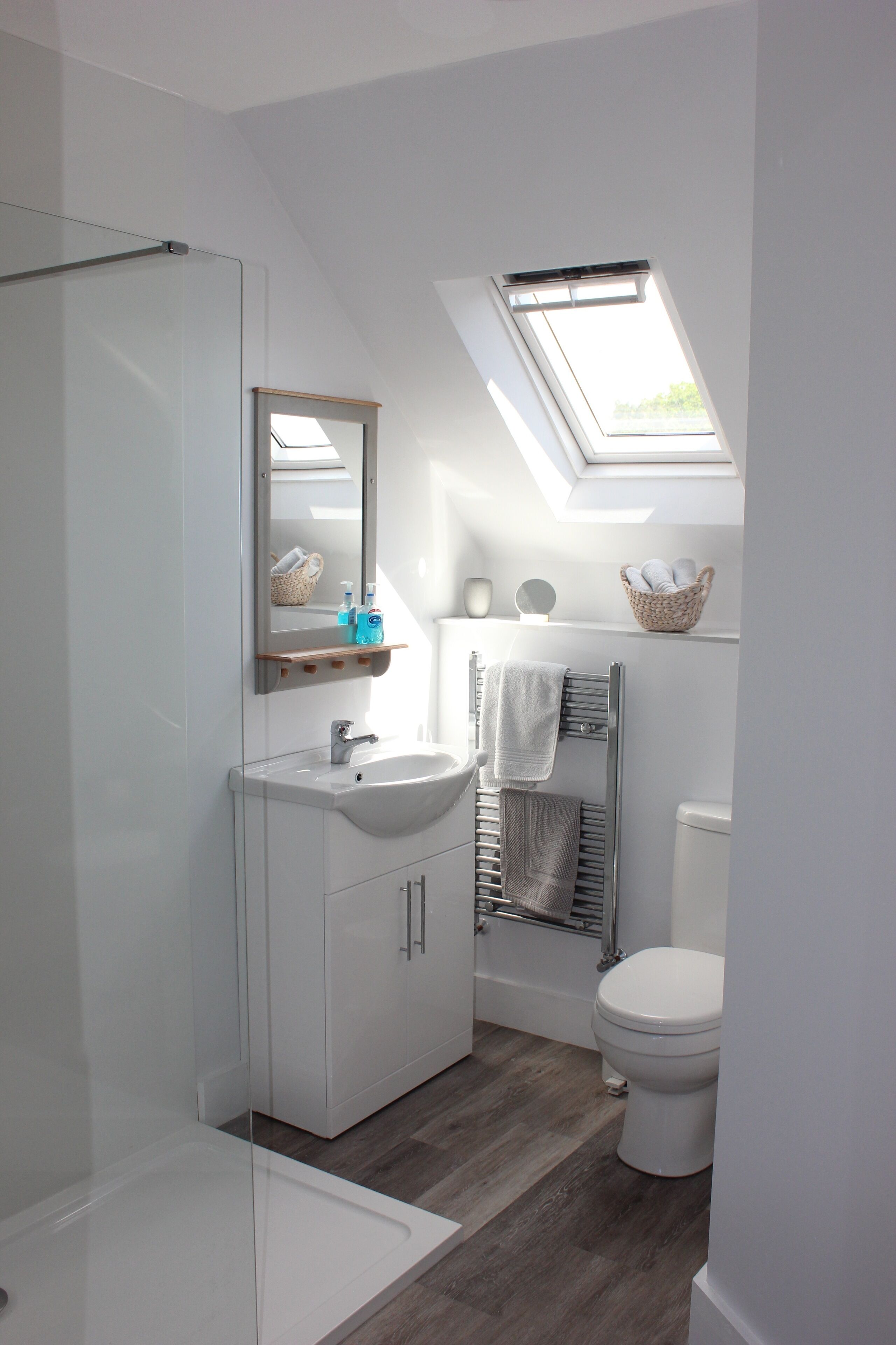 Une salle de bain moderne avec un puits de lumière, un lavabo blanc, une baignoire et des toilettes.