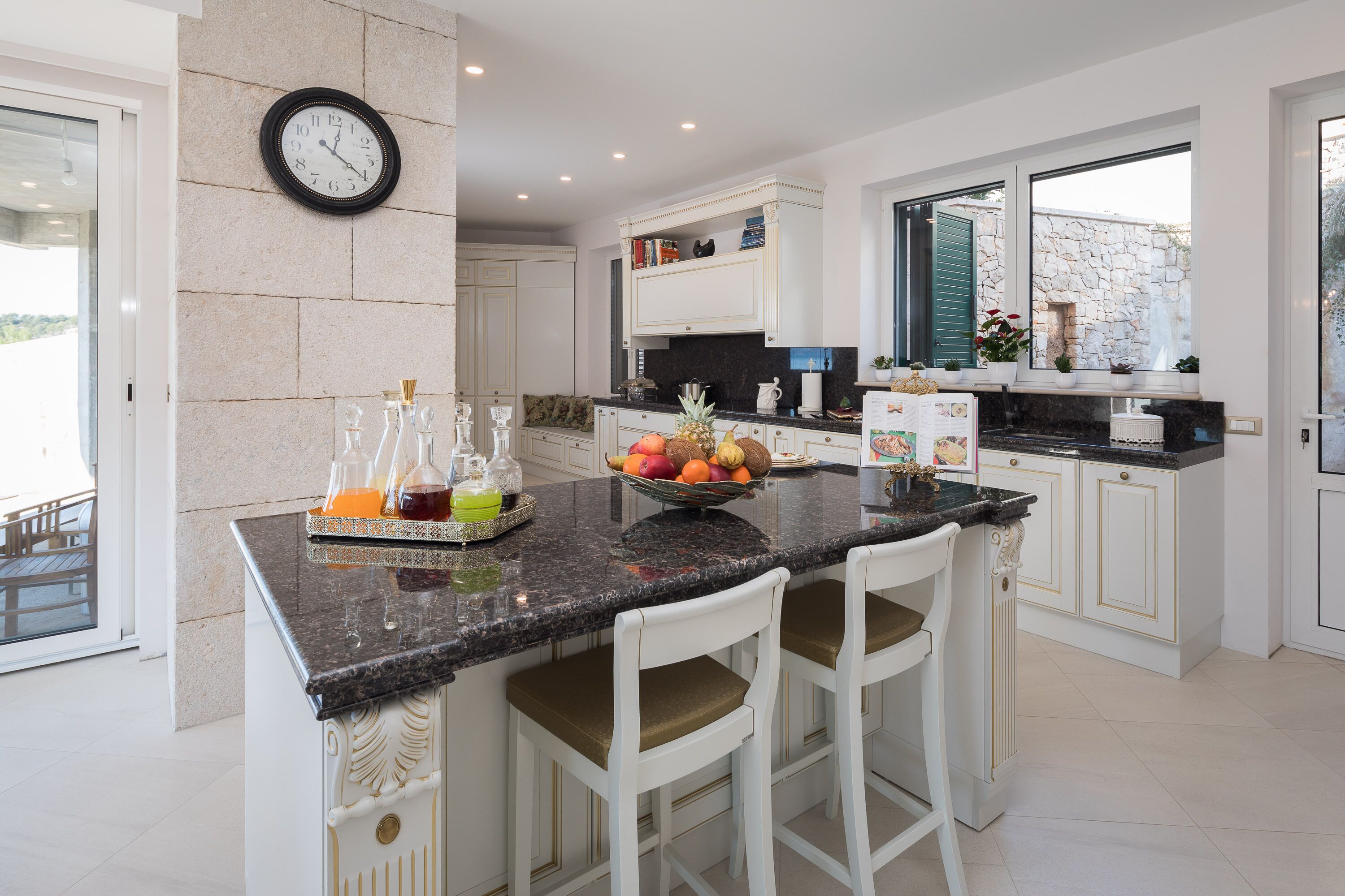A modern kitchen with a granite countertop, white cabinetry, and a fruit bowl.