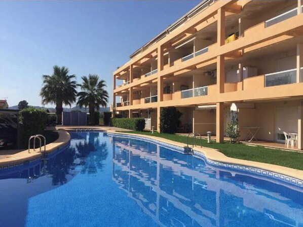 Un hôtel à plusieurs étages doté d’une piscine, de balcons et de palmiers.