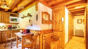 Un interior de madera con zona de cocina, una mesa de comedor de madera, sillas y un banco.