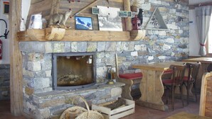 Un interior rústico con chimenea de piedra, vigas de madera y pared de piedra.