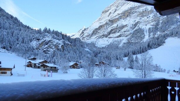 Un paisaje montañoso cubierto de nieve con cabañas de madera y barandilla de balcón de madera.