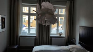 Una camera d'hotel con un letto, una finestra con tende, un termosifone e un quadro appeso al muro.