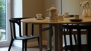 Zona pranzo con tavolo apparecchiato per due, con teiera, tazze e un vaso.