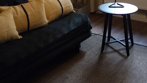 Un soggiorno moderno con un divano scuro, un tavolino rotondo e un lampadario originale.