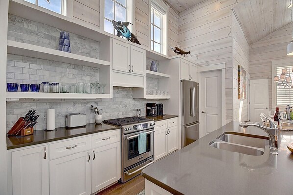 Una cocina moderna con armarios blancos, un refrigerador de acero inoxidable e una isla central con pileta.