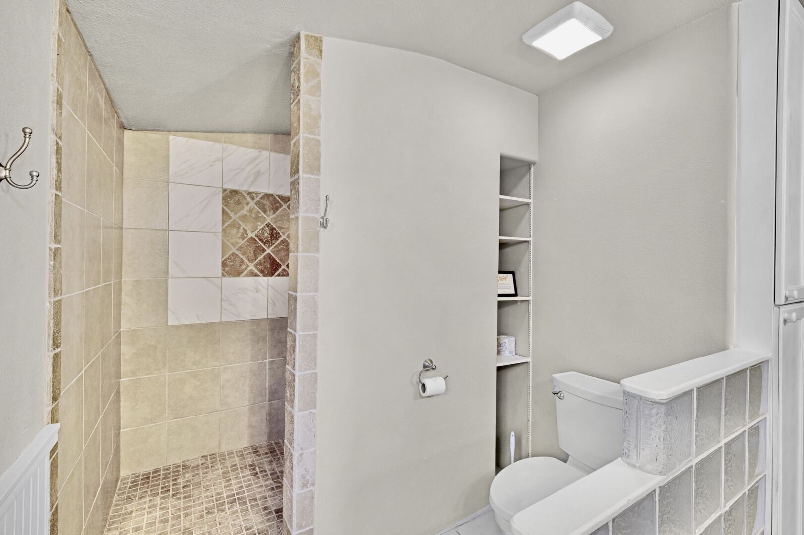 A bathroom with a shower, toilet, and storage shelves.