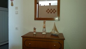 Un aparador de madera con un espejo encima, un modelo de barco pequeño y una botella decorativa.