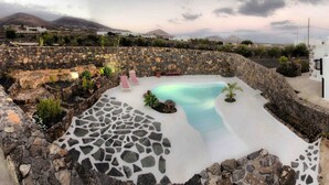 A pool area with stone walls and lounge chairs, surrounded by a stone wall and plants. - Casa de Los Olivos (Macher)