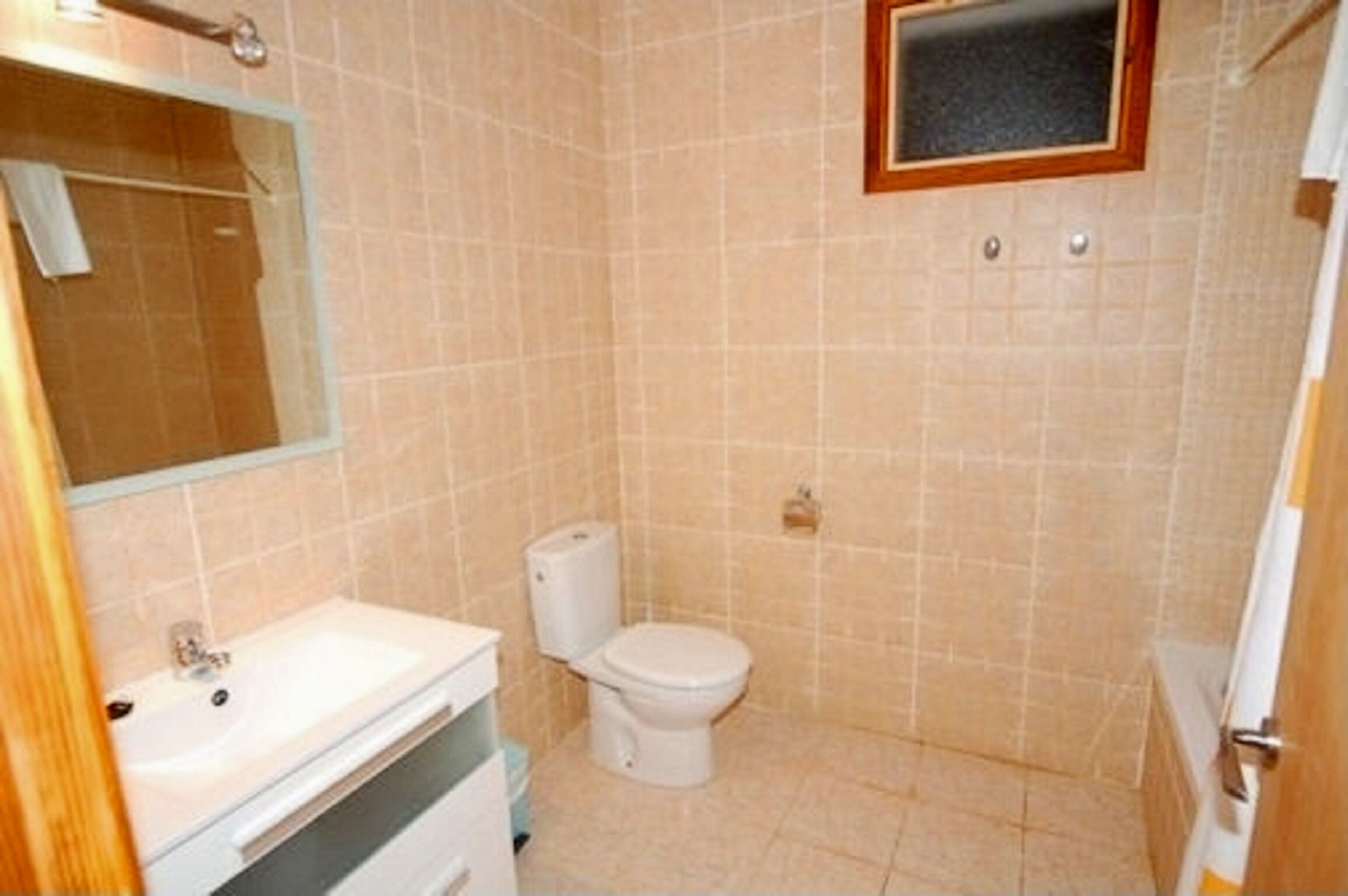 A small bathroom with a toilet, sink, and mirror.