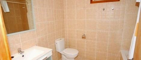 A small bathroom with a toilet, sink, and mirror.