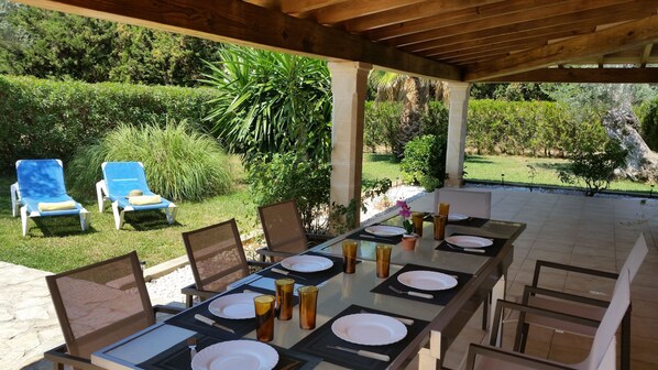 An outdoor dining area with a table set for four, surrounded by chairs, under a wooden pergola. - FANTASTIC VILLA WITH POOL (Pollença)