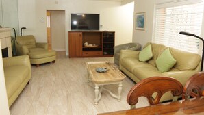 A living room with a TV, two sofas, a coffee table, and a dining table.