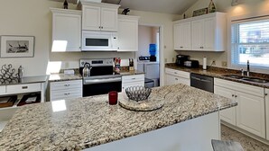 Eine moderne Küche mit weißen Schränken, Granit Arbeitsplatten, einem eingebauten Backofen, einer Mikrowelle und einem Geschirrspüler.