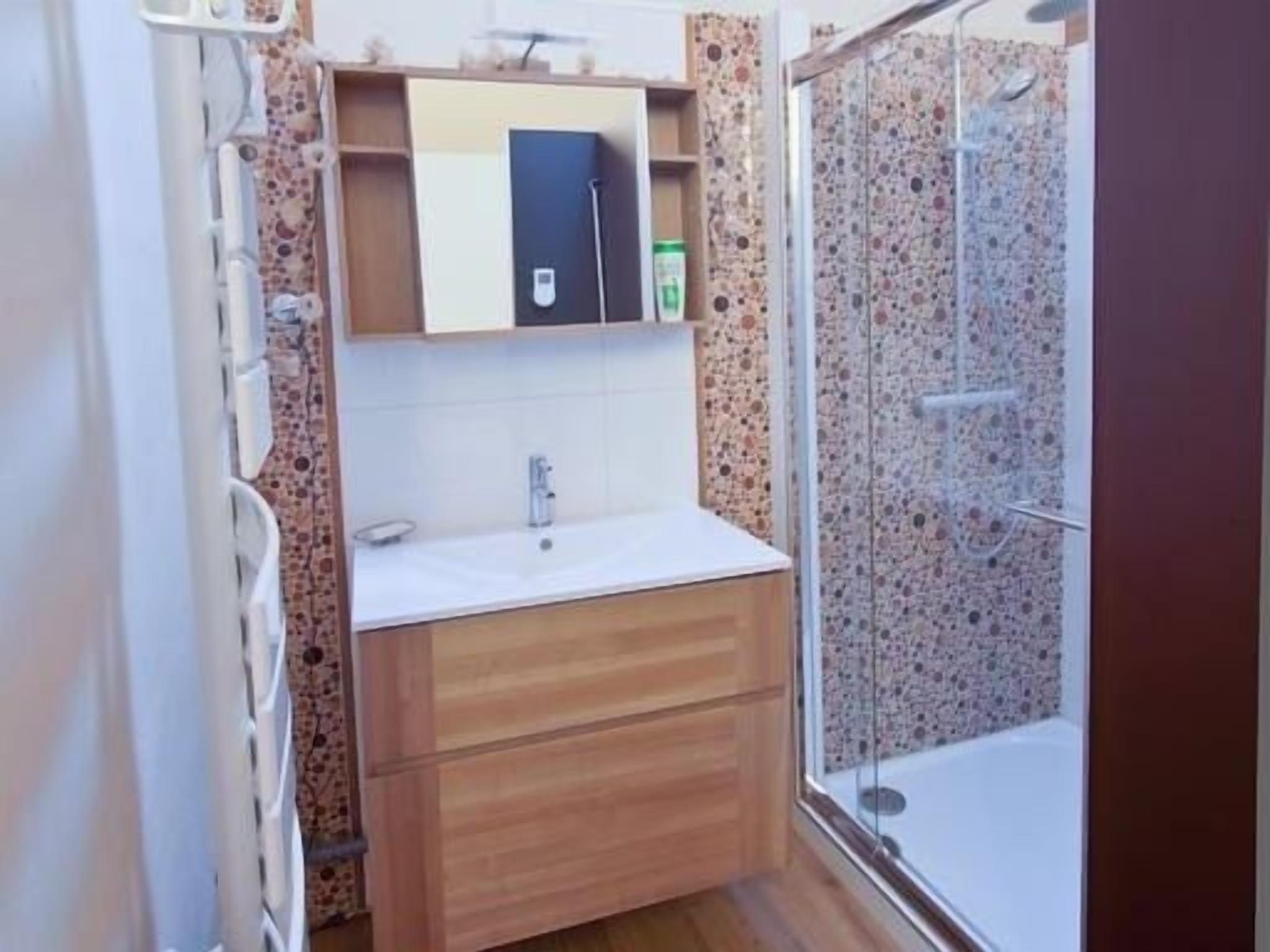 Un baño con ducha, lavamanos y espejo.
