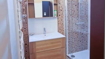 Un baño con ducha, lavamanos y espejo.