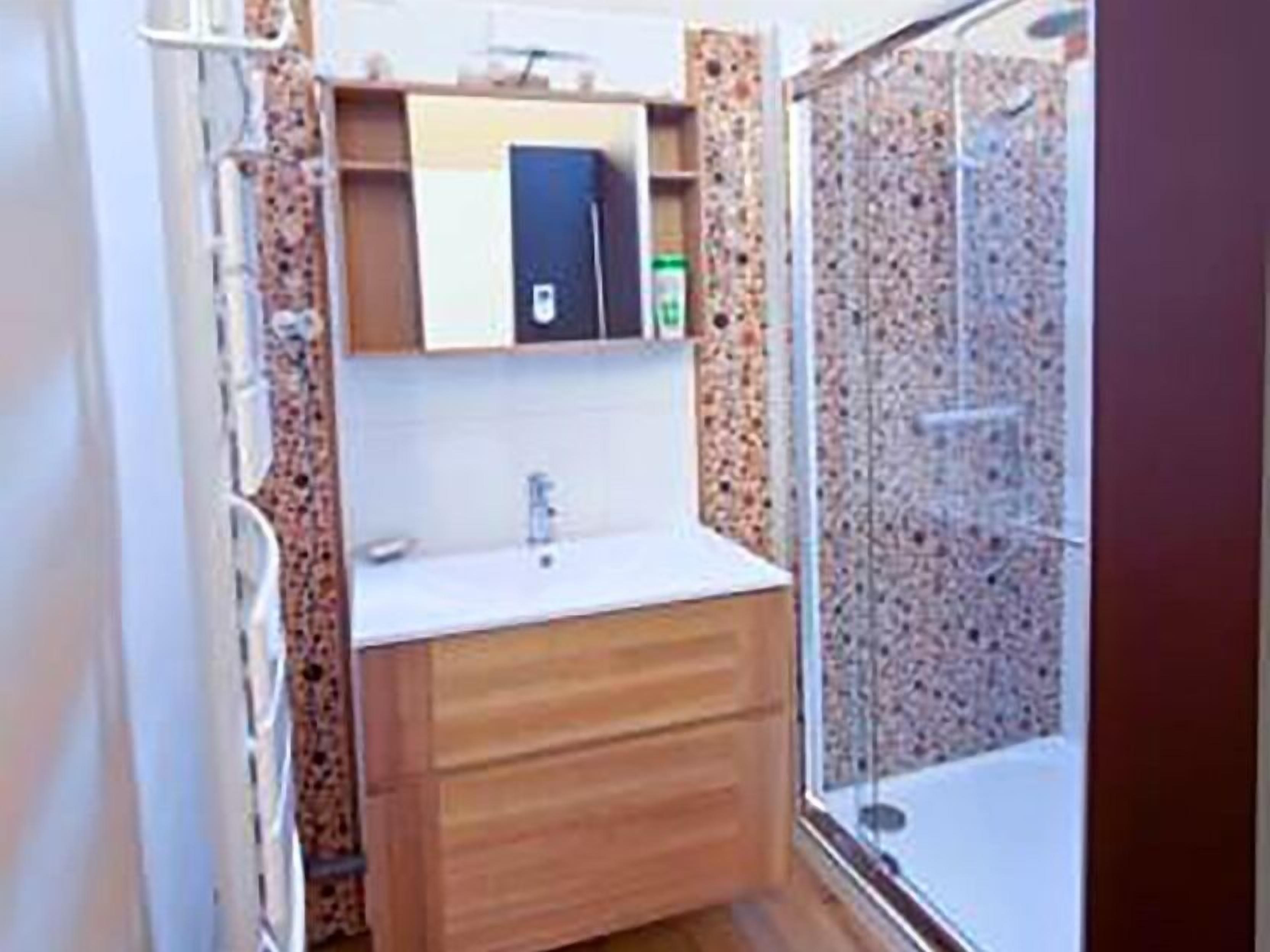 Un baño con tocador de madera, lavamanos y cabina de ducha.