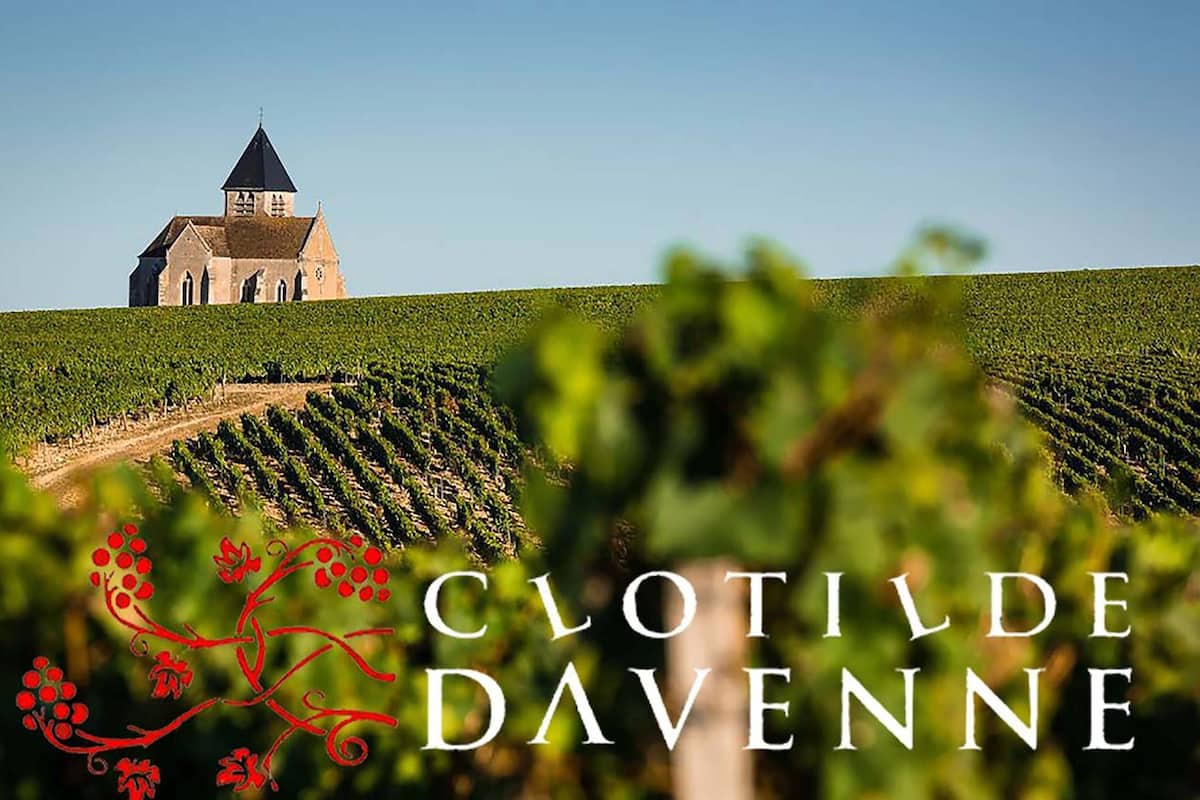 Ein Weinberg mit Rebenreihen und einer Kirche im Hintergrund. Der Schriftzug 'Clotilde Davenne' und 'Chablis 1989' ist sichtbar.