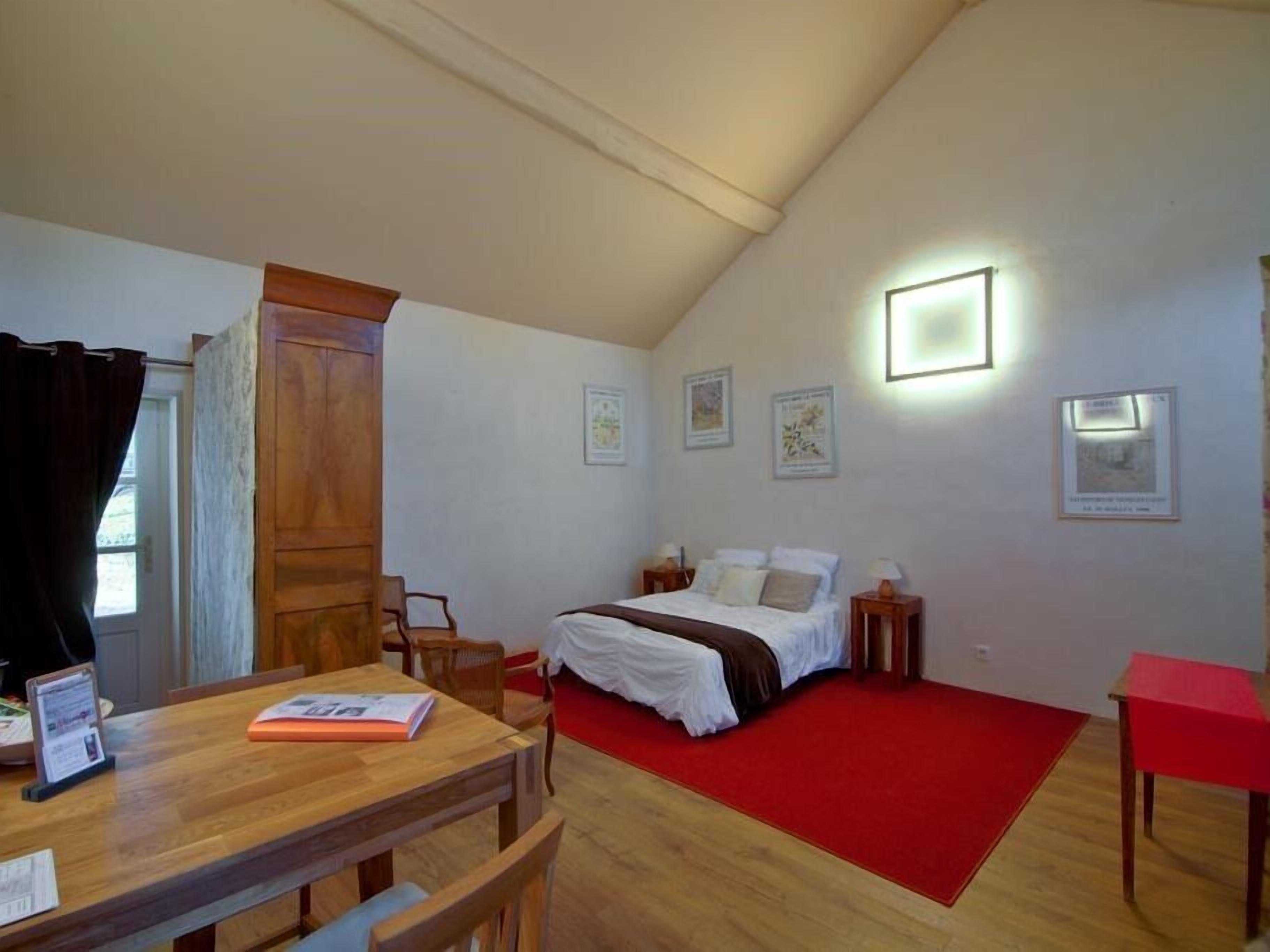 Un dormitorio con cama, escritorio y alfombra roja.
