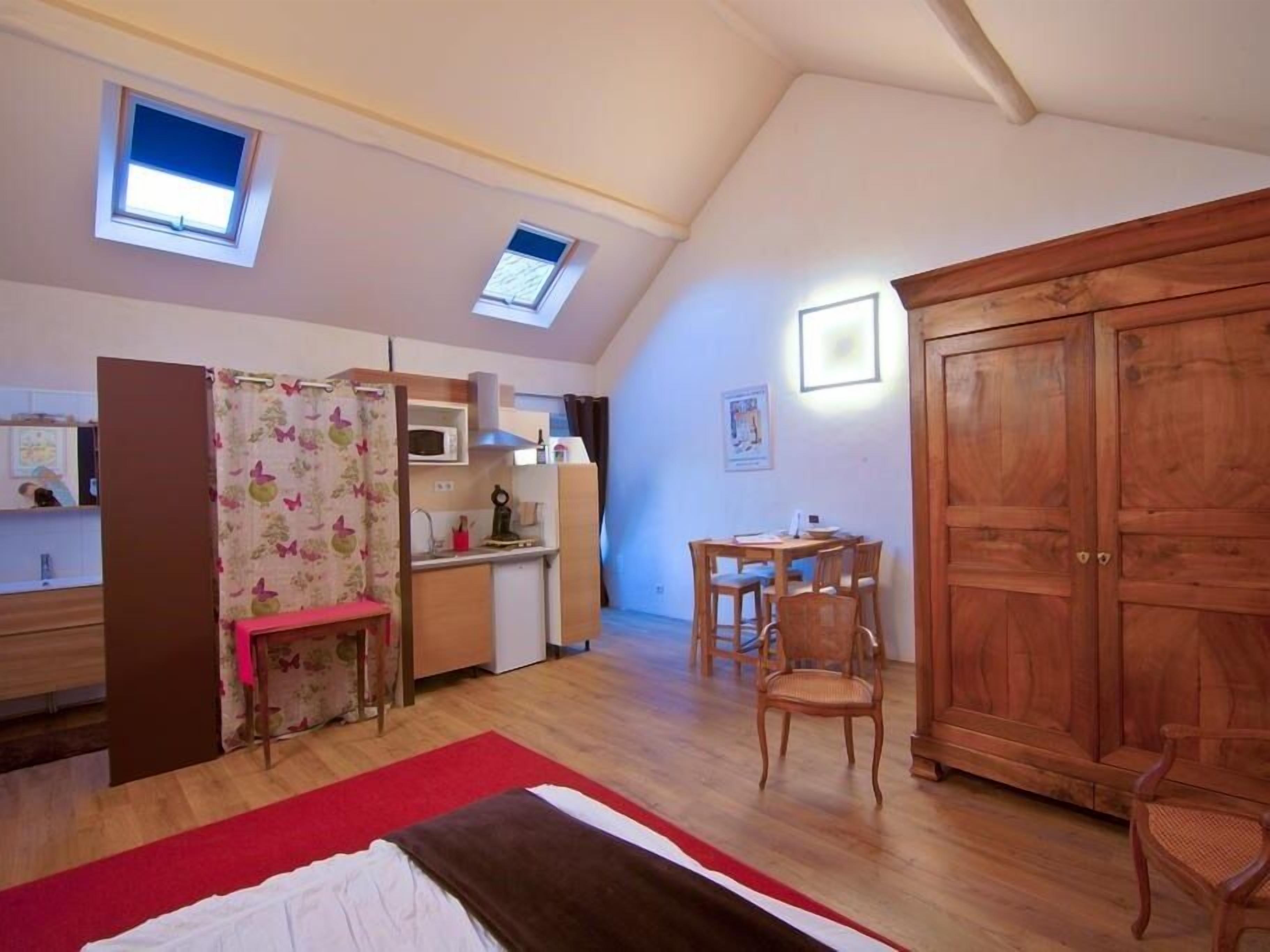A compact room with a kitchenette, a dining area, and a large wardrobe.