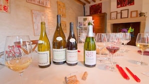 A wine tasting setup with bottles and glasses on a table, wooden beams on the ceiling, and framed artwork on the walls. - Les Temps Perdus (Prehy)