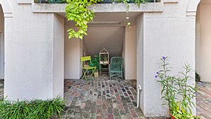 A courtyard with a brick floor, a green chair, a small table, and a potted plant. - Intimate Getaway for Two, Steps from Forsyth Park by Lucky Savannah (Savannah)