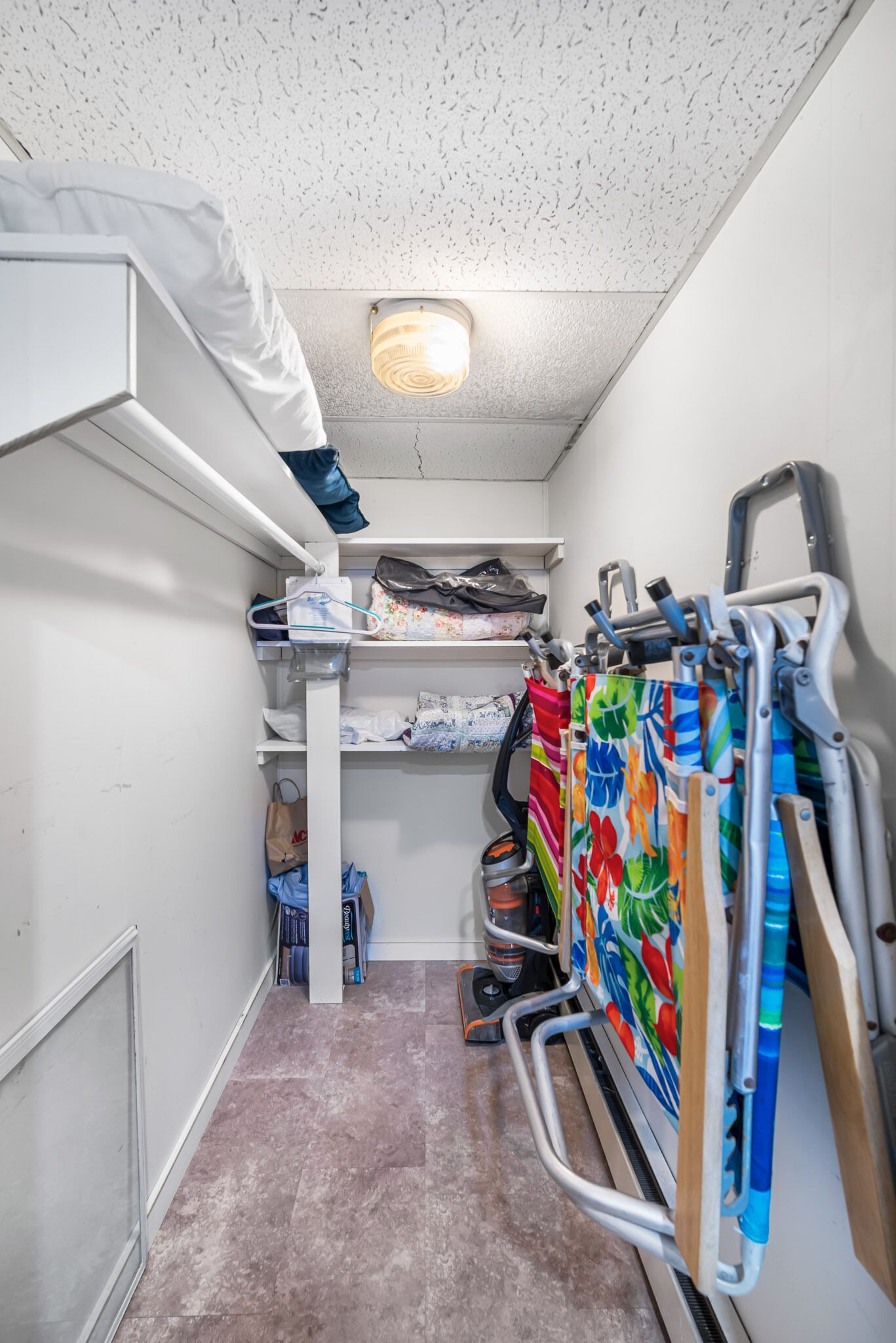 Habitación pequeña con literas, estantes de almacenamiento y espacio para silla de ruedas.