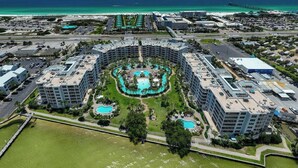 Un complexe hôtelier comprenant plusieurs bâtiments, un espace piscine central et une vue sur l’océan.