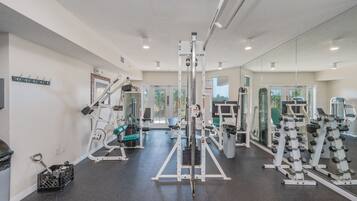 A gym with various exercise equipment, a mirror wall, and a door leading outside.