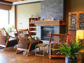 A cozy living room with a brick fireplace, wooden furniture, and a bookshelf.