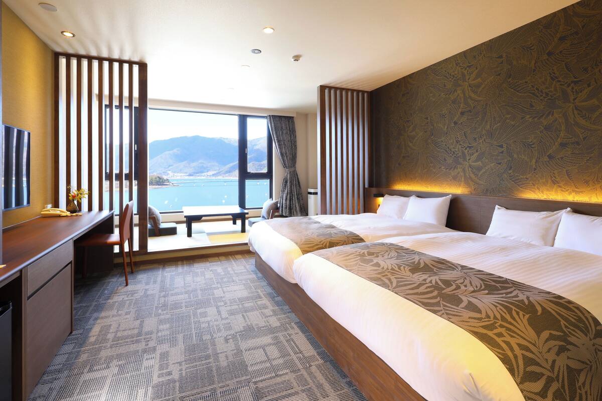 Una habitación de hotel con una cama grande, un escritorio y vista al mar.