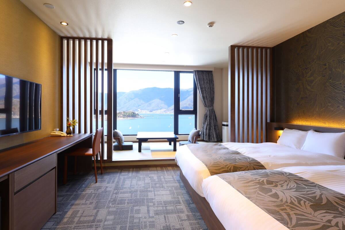 Habitación de hotel con una cama grande, un escritorio, una silla y vista al mar.