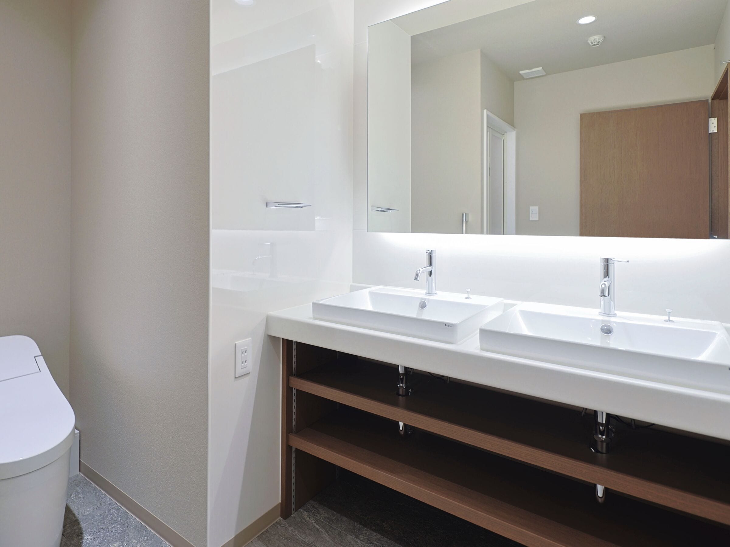 Un baño moderno con dos lavamanos, un espejo y un inodoro.