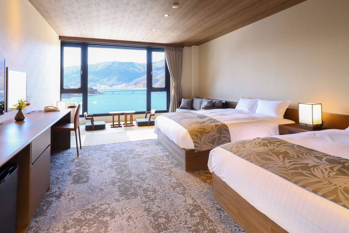 Habitación de hotel con dos camas, un escritorio, una silla y vistas al mar.