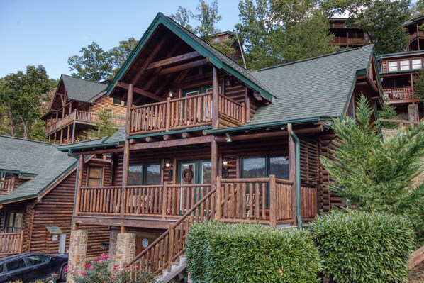 A log cabin with multiple balconies and a stone staircase.