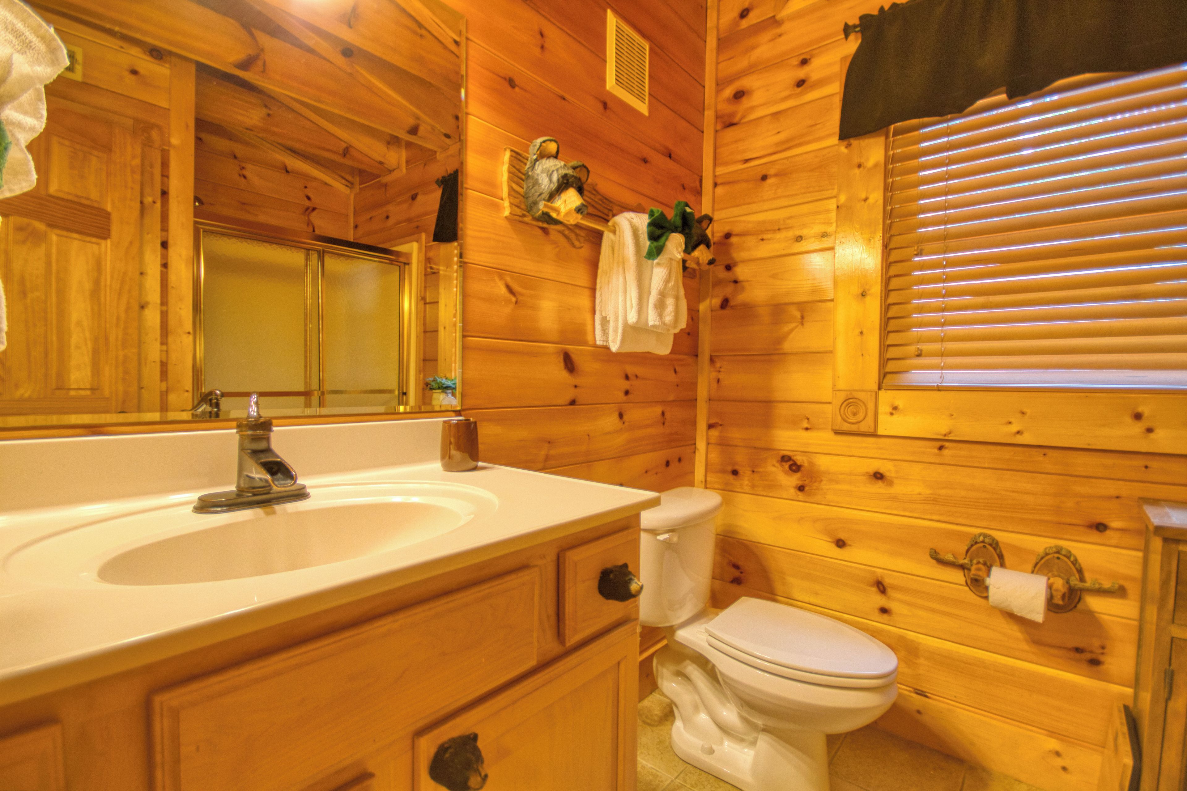 Ein Badezimmer einer Holzhütte mit Waschbecken, Toilette und Spiegel.