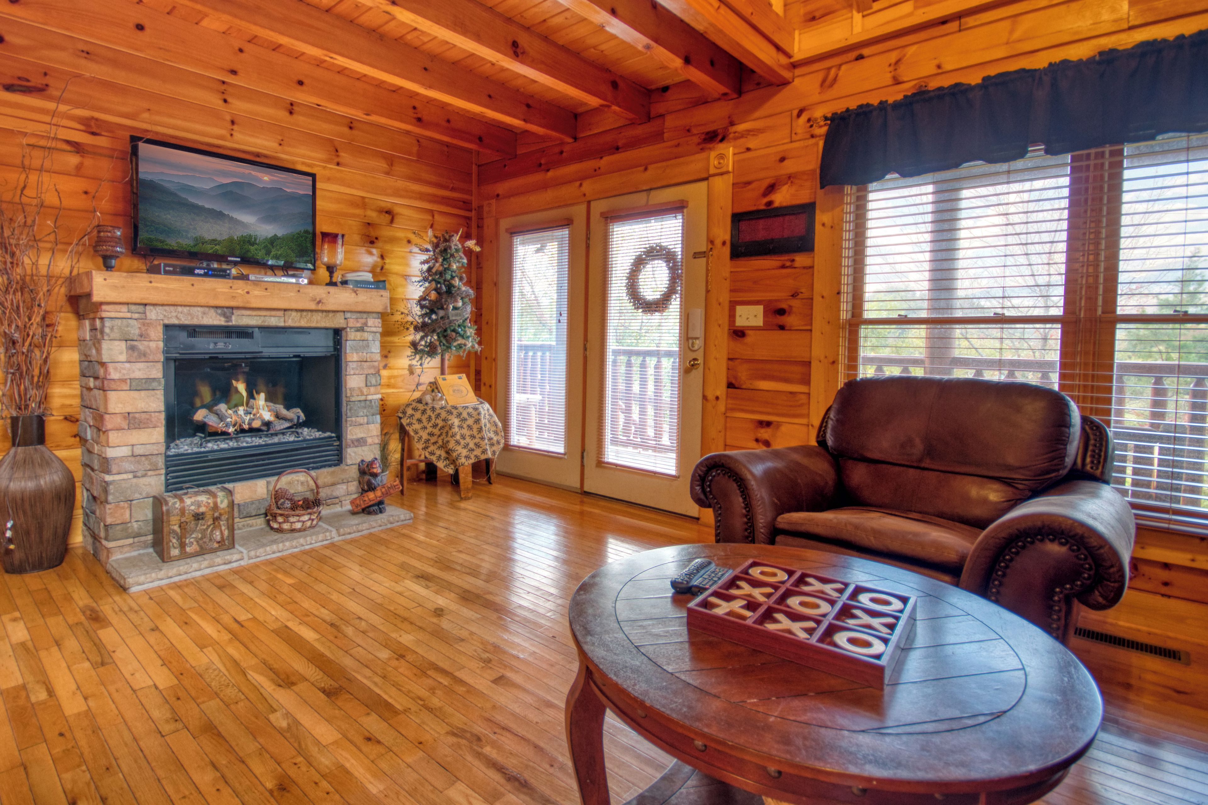 A cozy log cabin interior with a fireplace, leather sofa, and a table with a game.