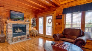 L’intérieur chaleureux d’un chalet en bois, avec une cheminée, un canapé en cuir et une table sur laquelle est disposé un jeu.
