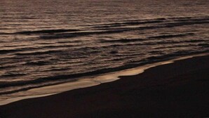 Ein Strand bei Sonnenuntergang, Wellen nähern sich dem Ufer.