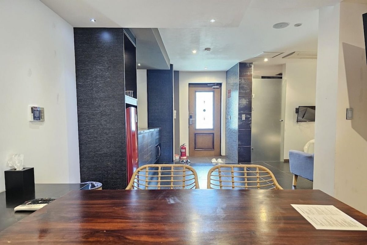 Un comedor moderno con una mesa y sillas de madera, un extintor y una puerta que da a otra habitación.