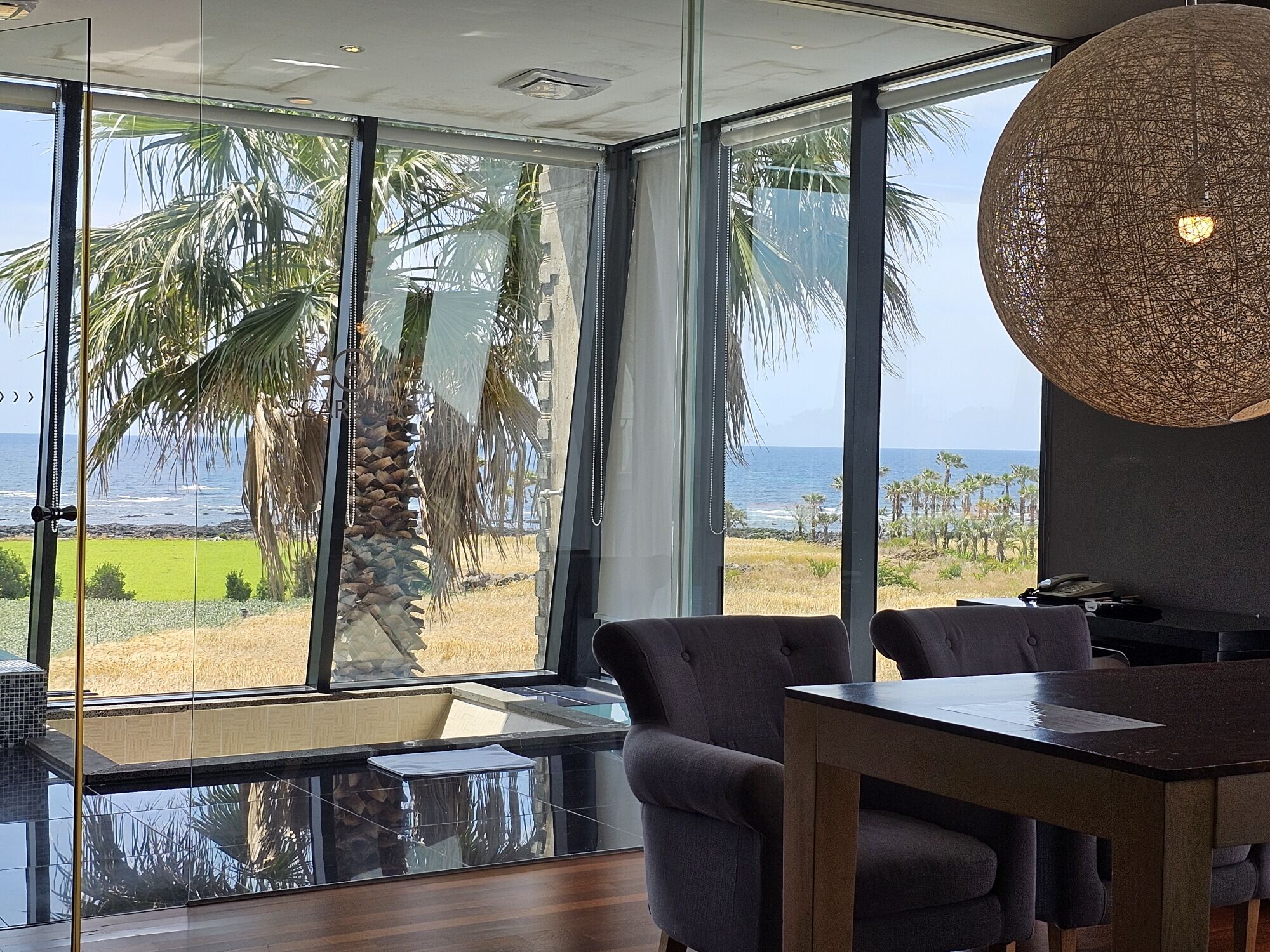 Een moderne kamer met grote ramen met uitzicht op het strand en de oceaan.