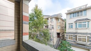 A residential building with a balcony, a staircase, and a tree in the background. - Dan Dan House (Tongluo)