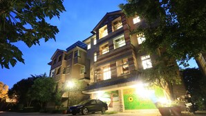 A multi-story building with a paved driveway and a parked car. - Dan Dan House (Tongluo)