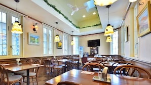 A restaurant with wooden tables and chairs, pendant lighting, and a large window. - Suzuka Royal Hotel (Suzuka)