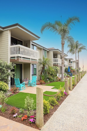 A multi-story hotel with balconies, a landscaped garden, and a paved walkway.