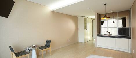 A modern apartment with a dining area, kitchenette, and a large window.